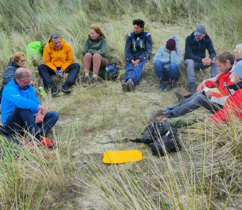 Trail groep zit in een cirkel in de duinen