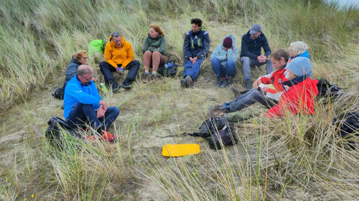 Trail groep zit in een cirkel in de duinen