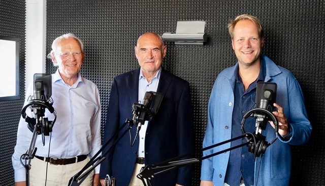 Drie mannen met microfoons in een podcast studio