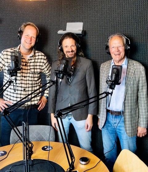 Drie mannen voor microfoons met koptelefoons op