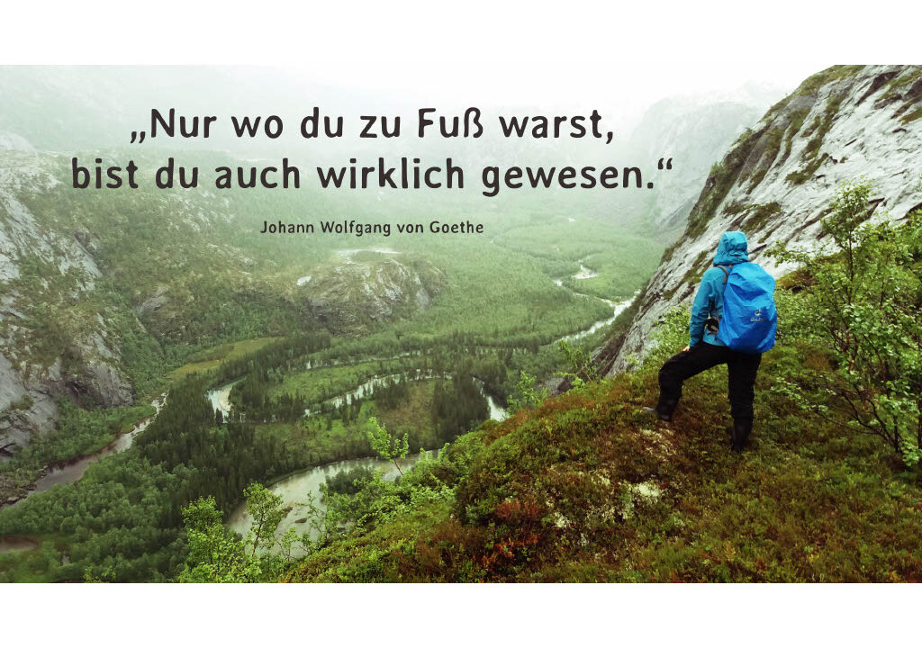 Persoon kijkt uit over een vallei met het Goethe-citaat 'Nur wo du zu Fuß warst, bist du auch wirklich gewesen.'