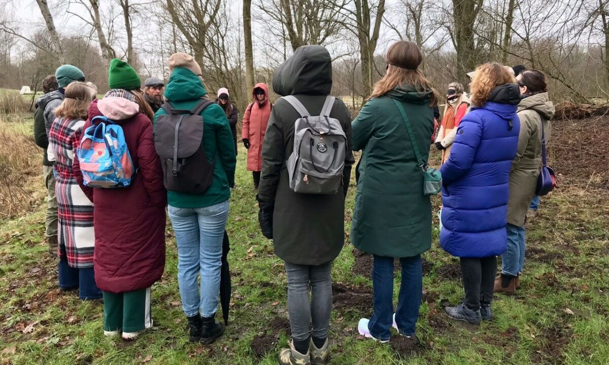 Groep warm gekleede mensen staat in een kring in het Amsterdamse bos