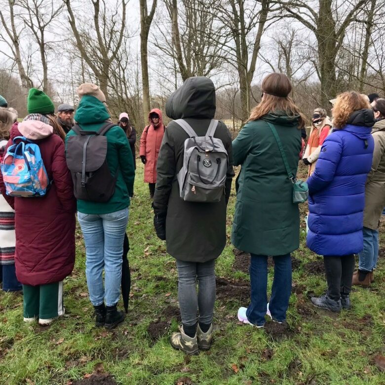 Groep warm gekleede mensen staat in een kring in het Amsterdamse bos