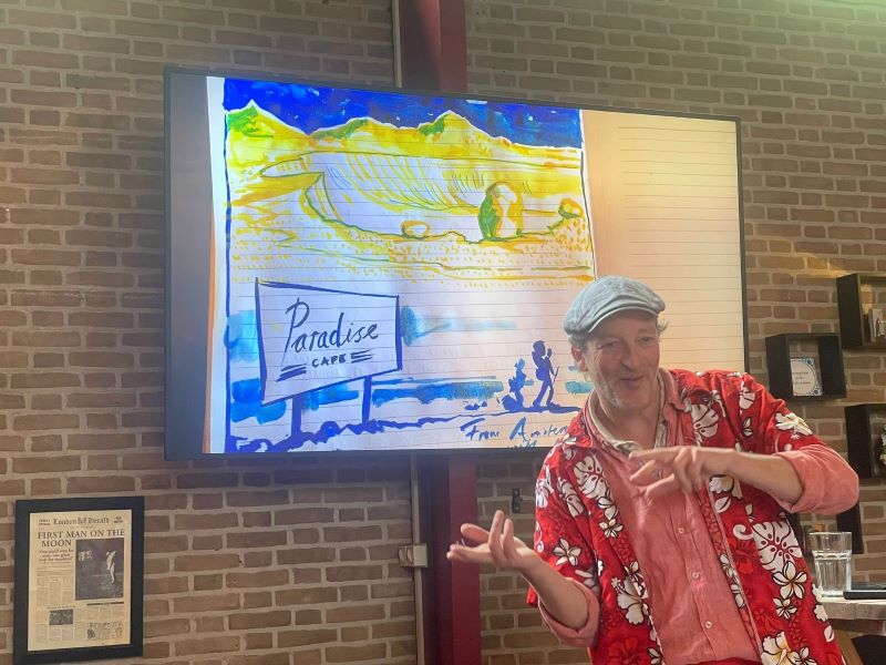 Tim Voors presenteert voor een schilderij met opschrift 'Paradise Cafe